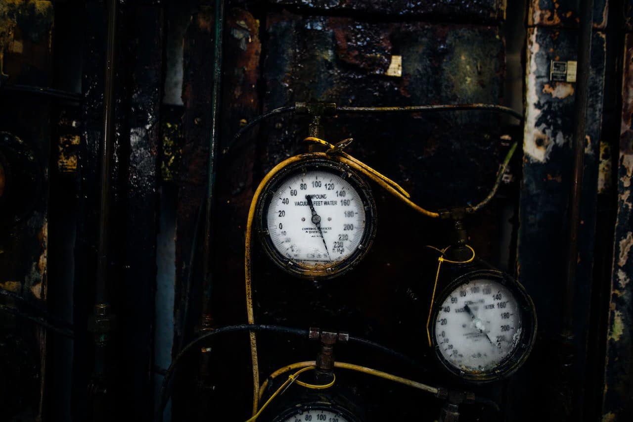 A dirty and rustic gauge with yellow wires on a black tank