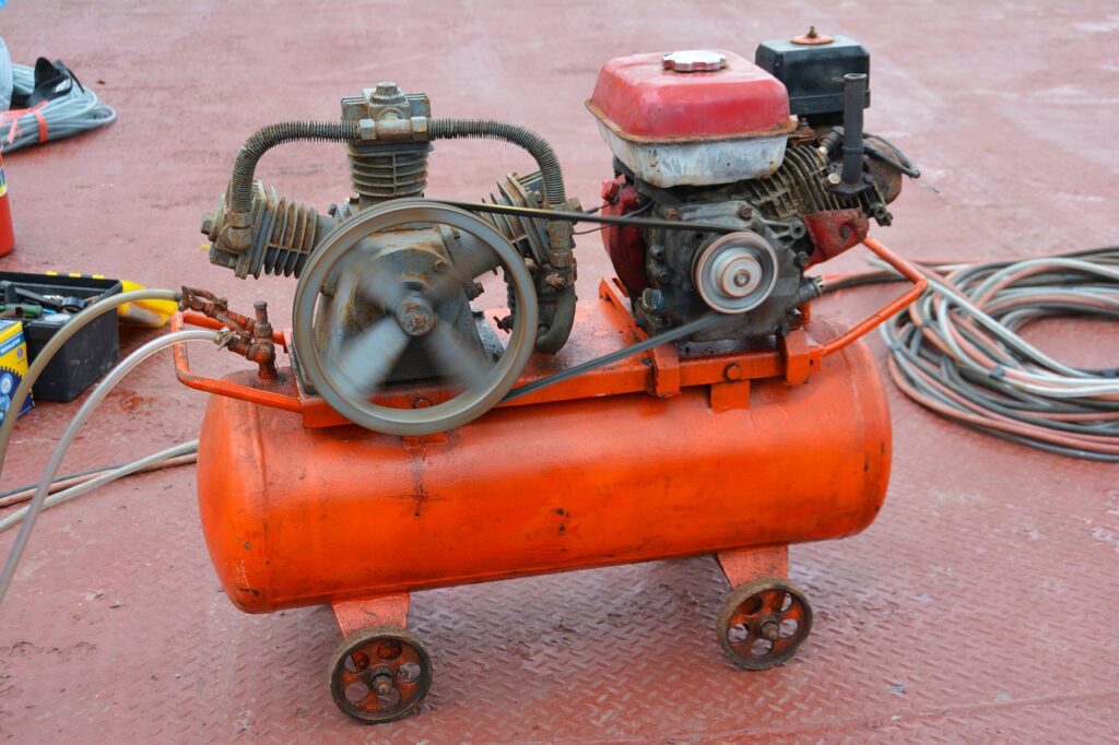 An orange compressor near a black and yellow toolbox on top of a red metal floor