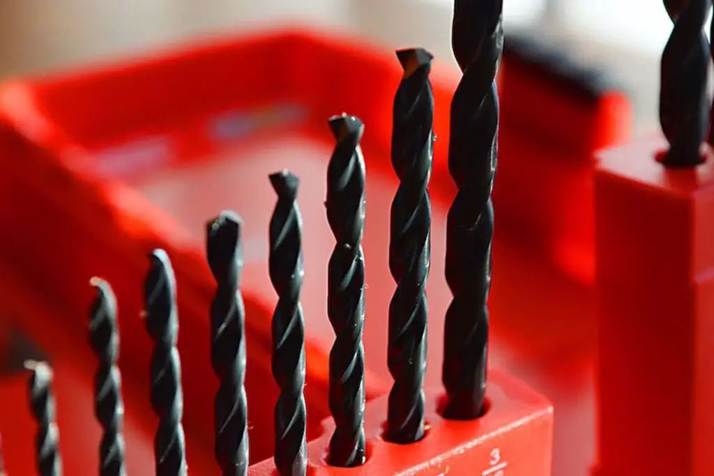 Black drill bits all lined upright on their tool box