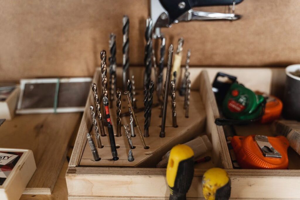 Drill bits placed on slots in a wooden organizer alongside other carpentry tools
