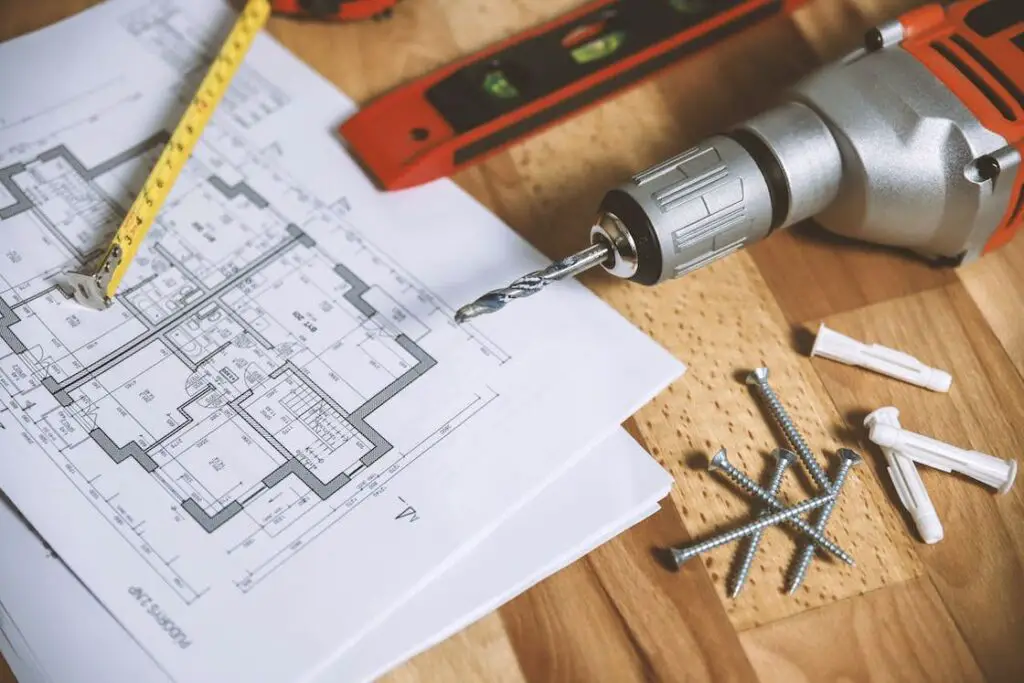 Floor plan beside a drill, screws and other carpentry tools