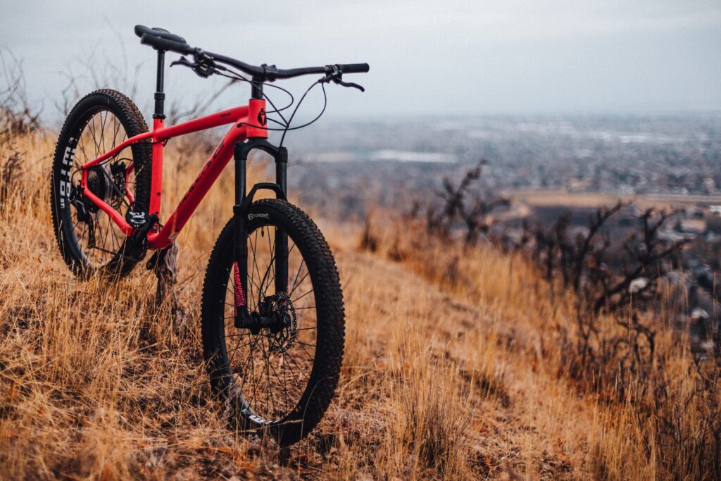A red and black bike parked on a brown hill covered with dried grass