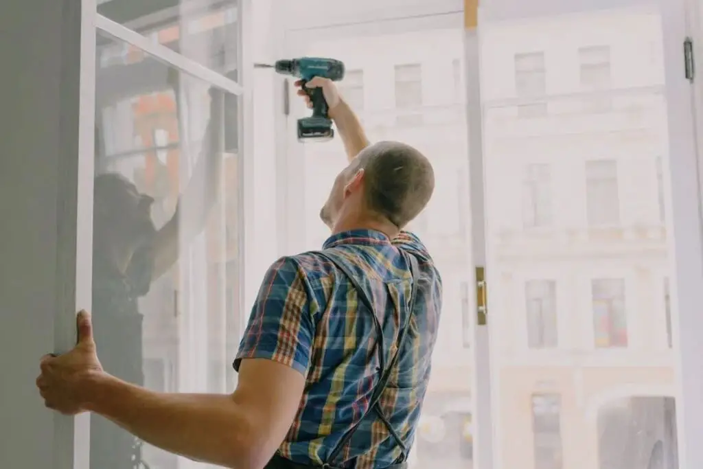Man using a drill to fasten screws for a white window