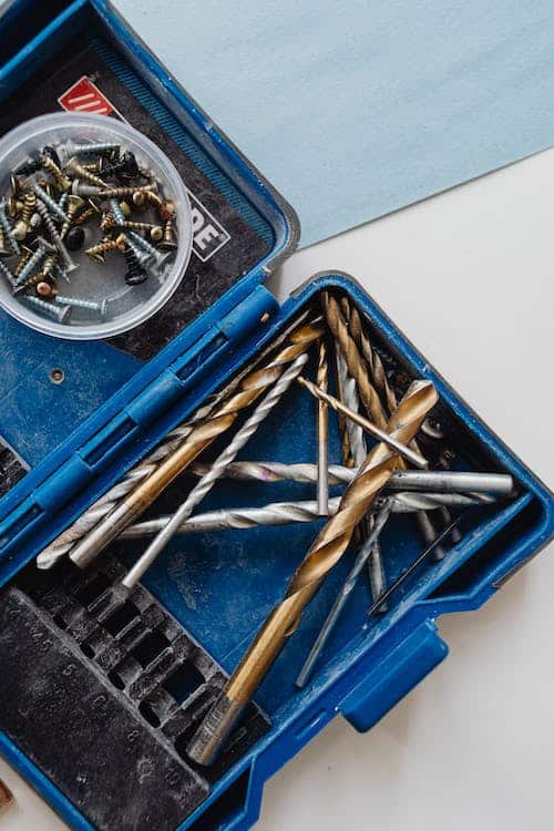 Various kinds of drill bits and screws in an opened blue container