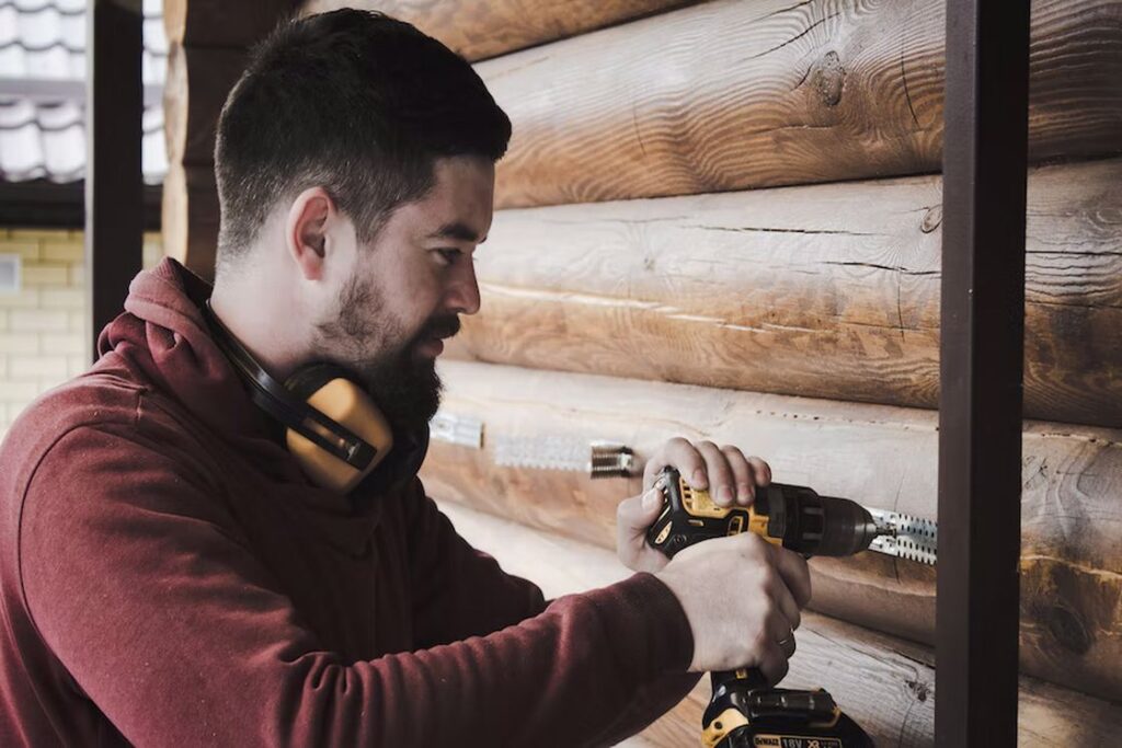 Man drilling a hole in the wooden walls