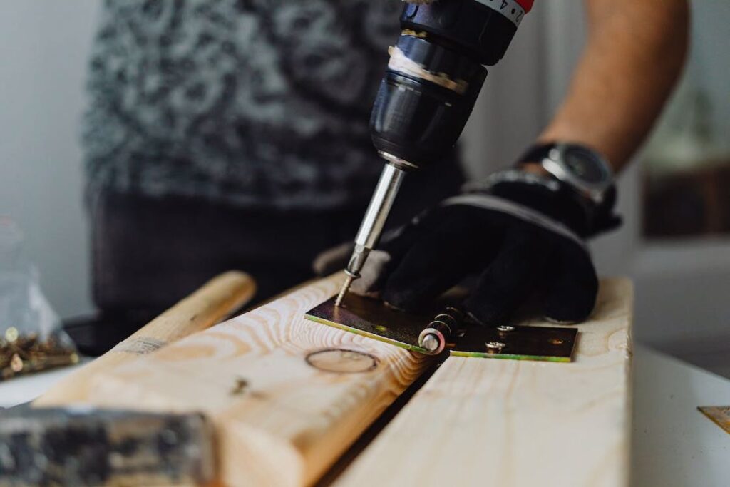 Person fastening screws into a wooden panel with a drill