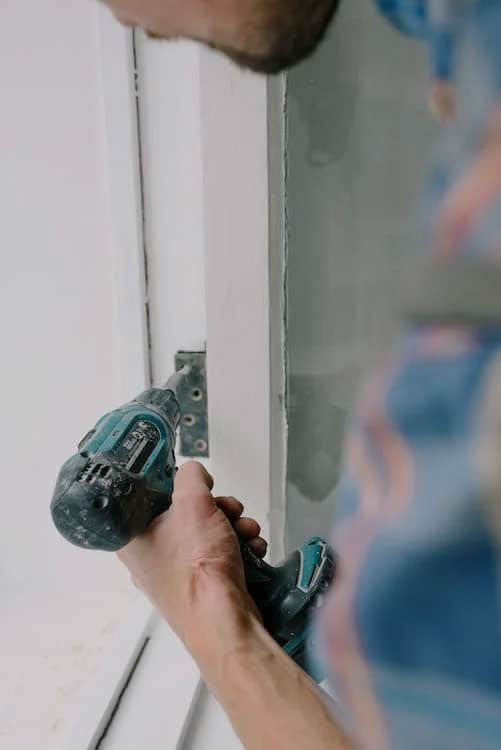 Man using a drill to fasten screws for a window