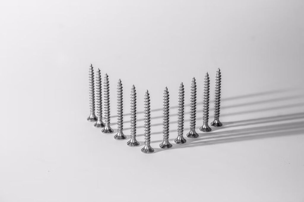 Silver screws placed upright and forming a V on a white table