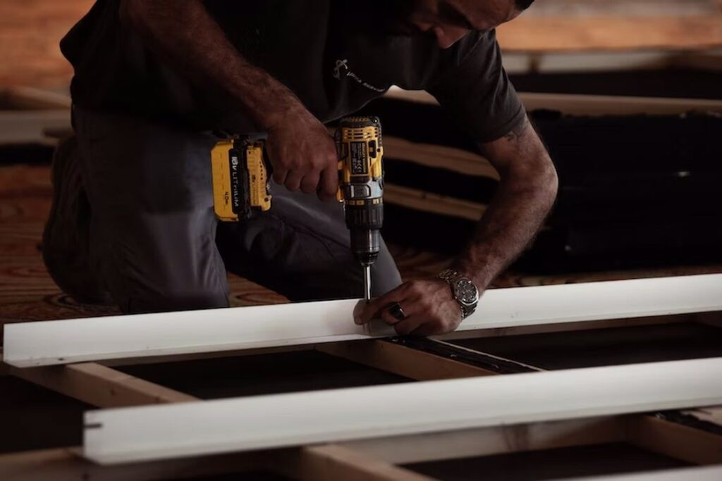 Man fastening a screw with a drill on a wooden project