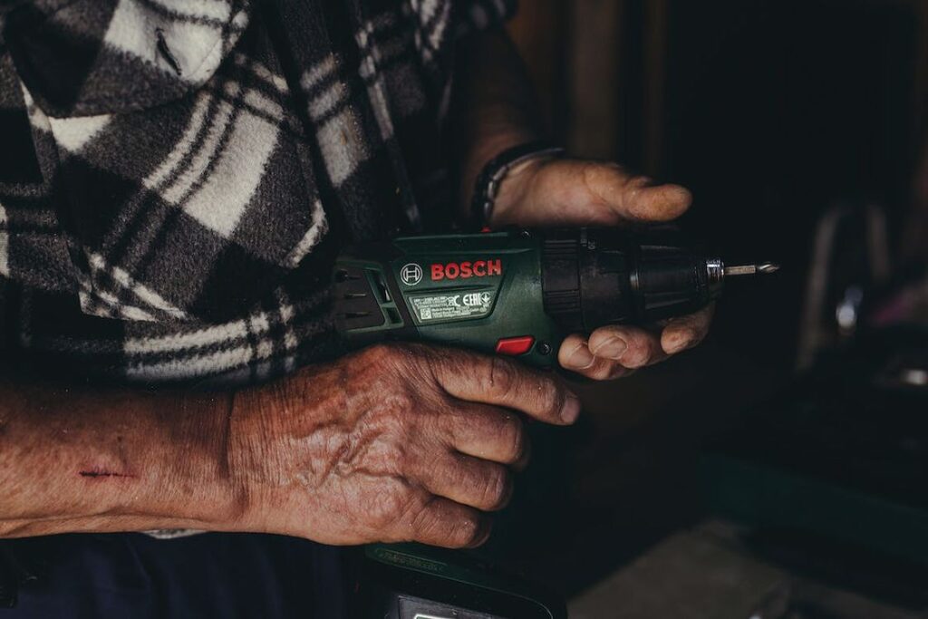 Man holding a green Bosch cordless drill