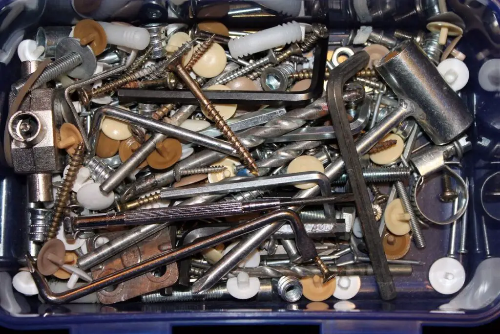 Drill bits, screws and other tools mixed together in a plastic container