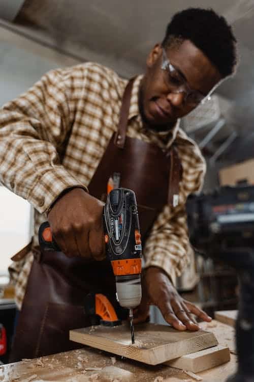 Man drilling a hole to a piece of wood