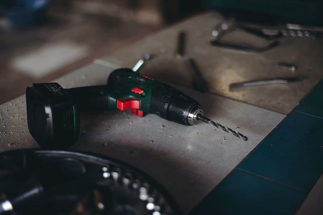 Green and black cordless drill placed in a table