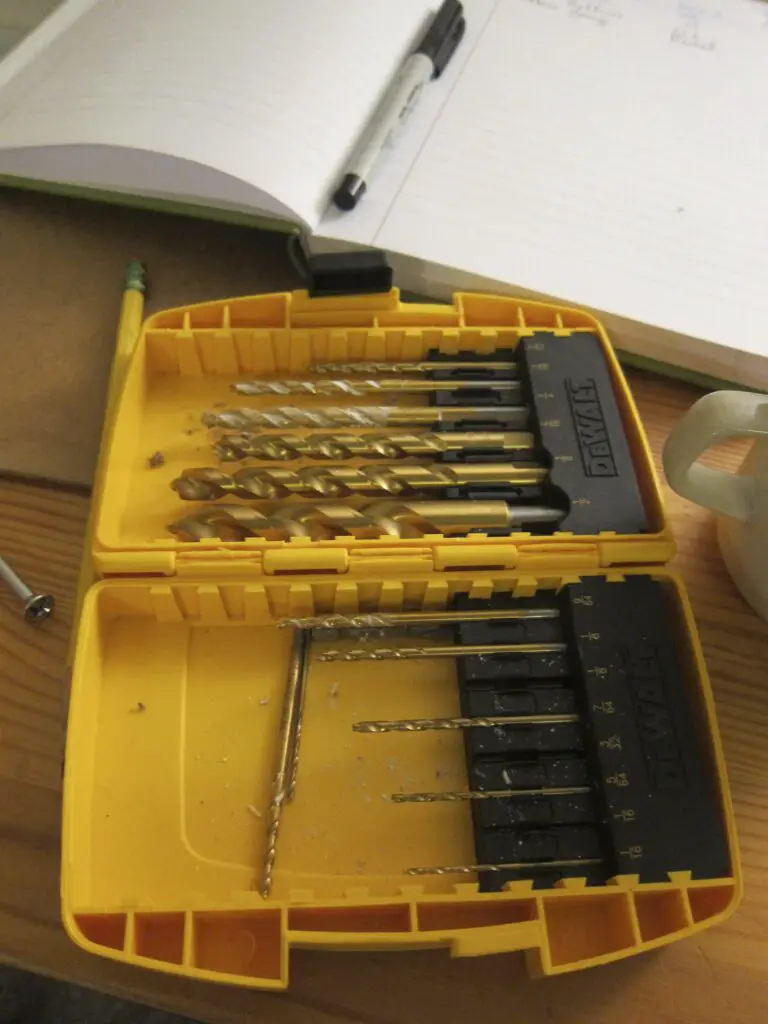 Drill bit placed inside its storage with an opened notebook beside it