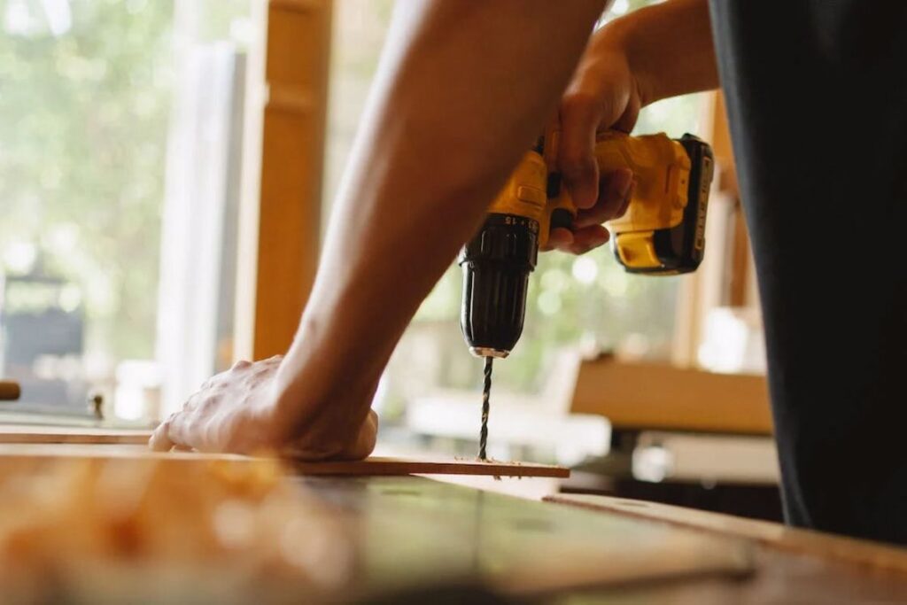 Man drilling a hole in a plank of wood