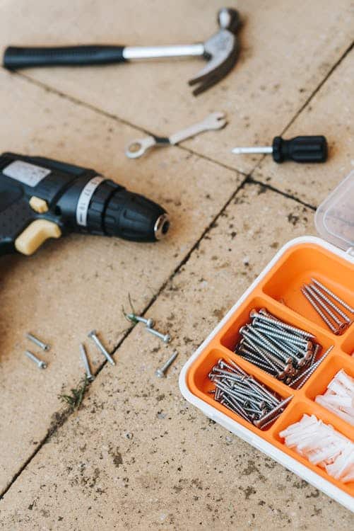 Drill and other repair tools like screws and nails stored in a container