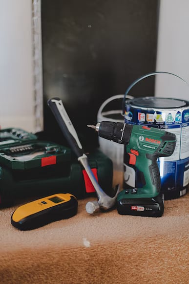 Drill, hammer, paint and other woodworking tools placed on the floor