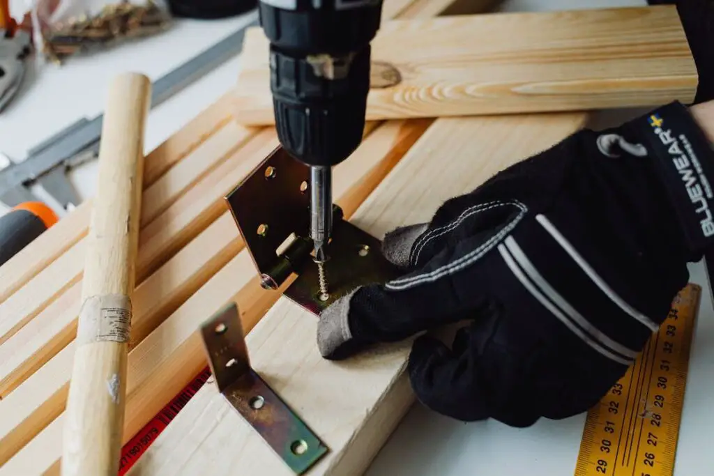 Man fastening a screw into a piece of wood by using a drill