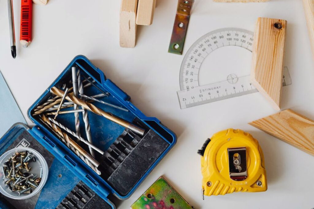 Different kinds of drill bits, screws and other woodworking tools are placed on a table