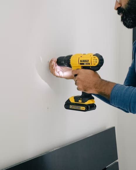 Man using a cordless drill to anchor into walls