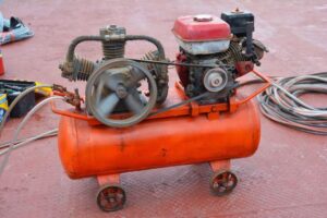 Orange air compressor placed on a red metal floor