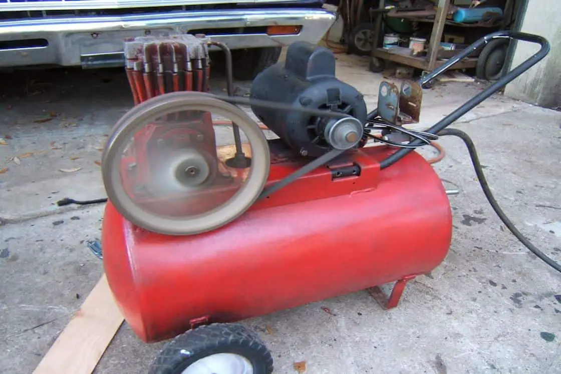 Red air compressor placed outdoors for garage work