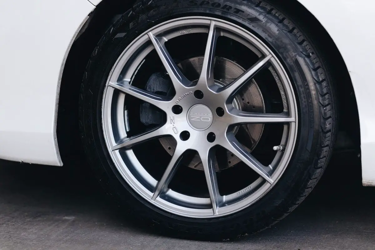 A black tire with a silver rim on a white car