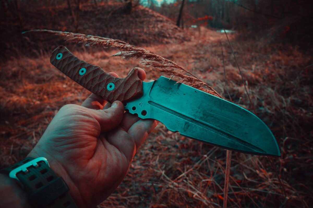 A person wearing a watch holds a knife with a brown handle