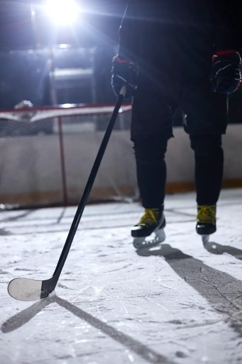 Ice hockey player holding a black hockey stick on an ice hockey rink
