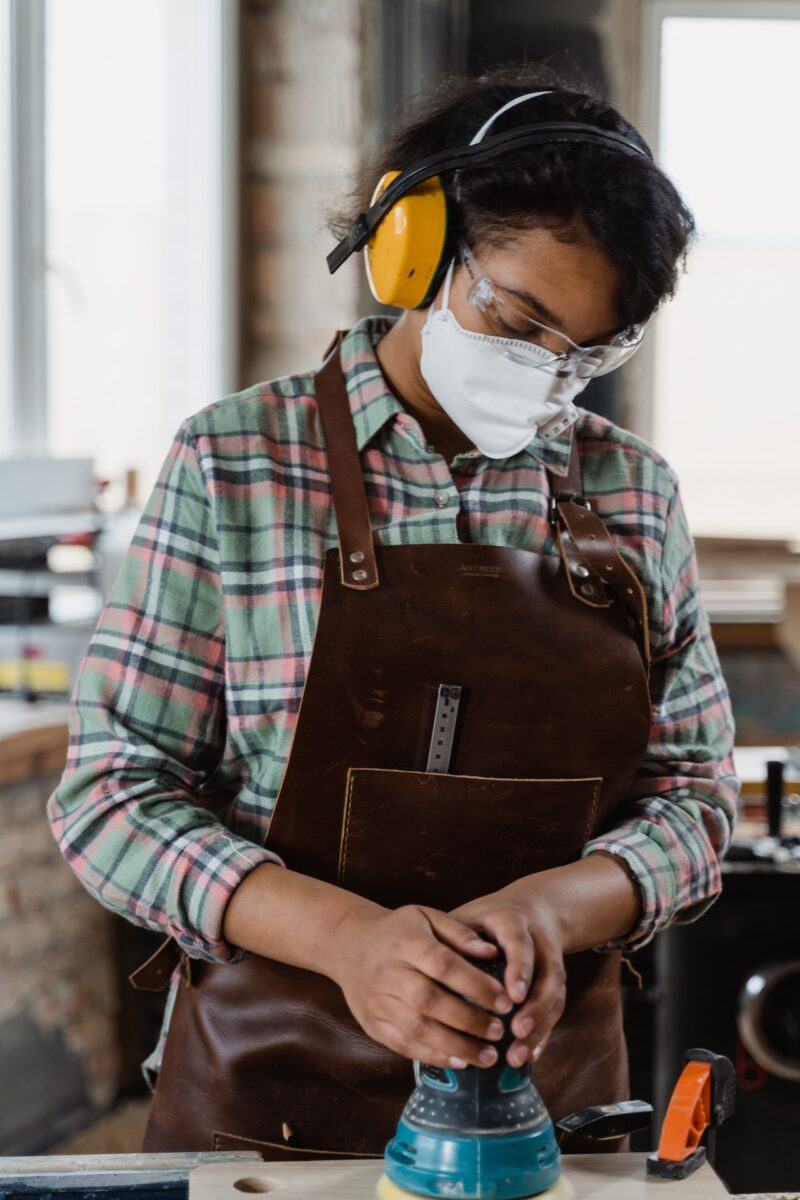 Woman wearing a striped long sleeves and protective gear in a leather apron using a Sandet