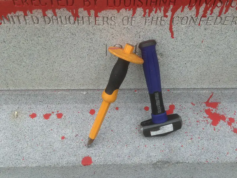 A hammer with a purple handle and a yellow chisel were placed on a cemented floor