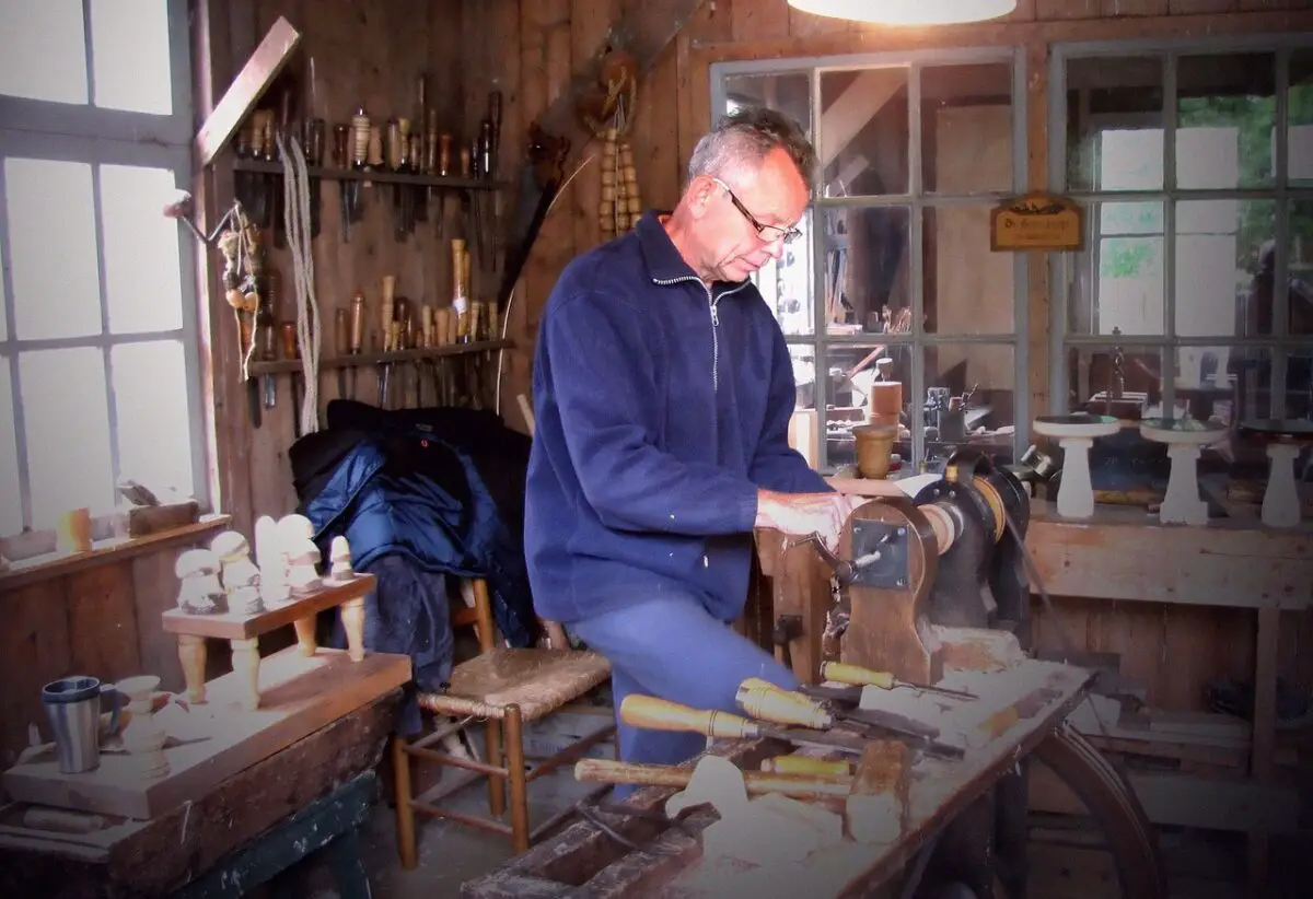 A man wearing a blue sweatshirt and pants using a tool for carpentry