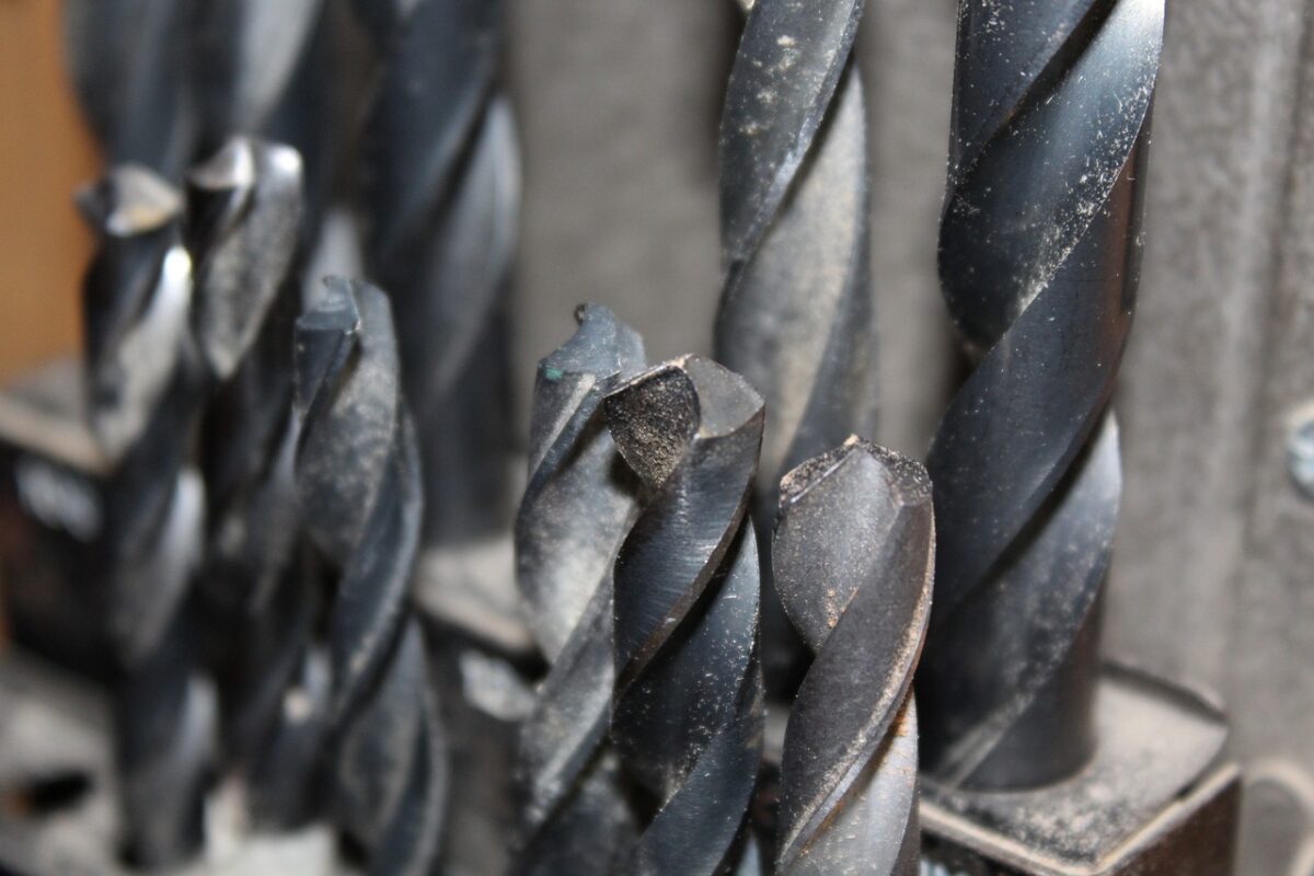 Black-colored drills on a black container near a metal wall