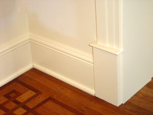A corner featuring a white baseboard and brown flooring