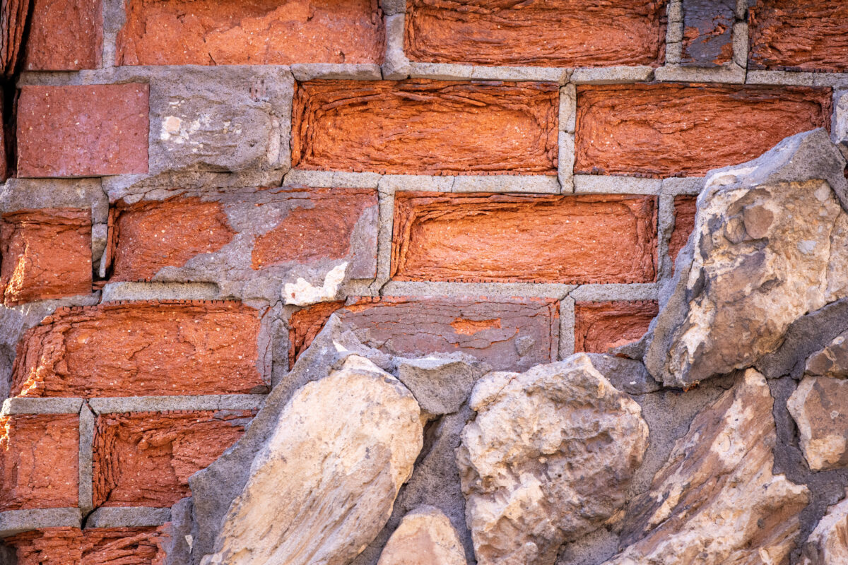 An orange brick piled together with cement and some rocks.