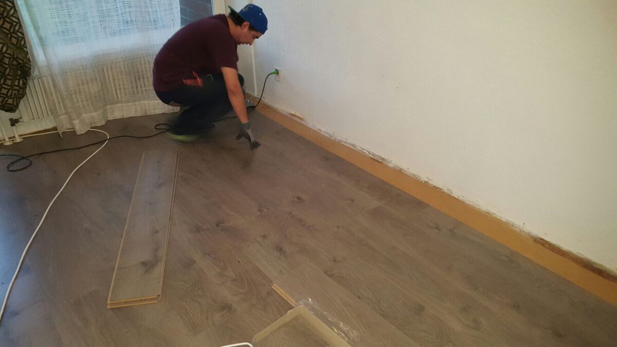 A man working on a room with laminated flooring