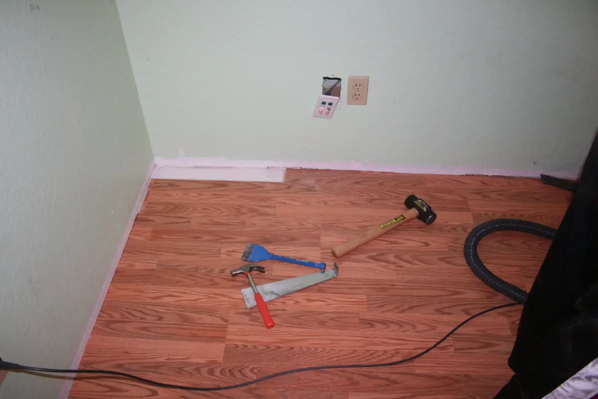 Laminated flooring with one missing piece at the corner together with some tools