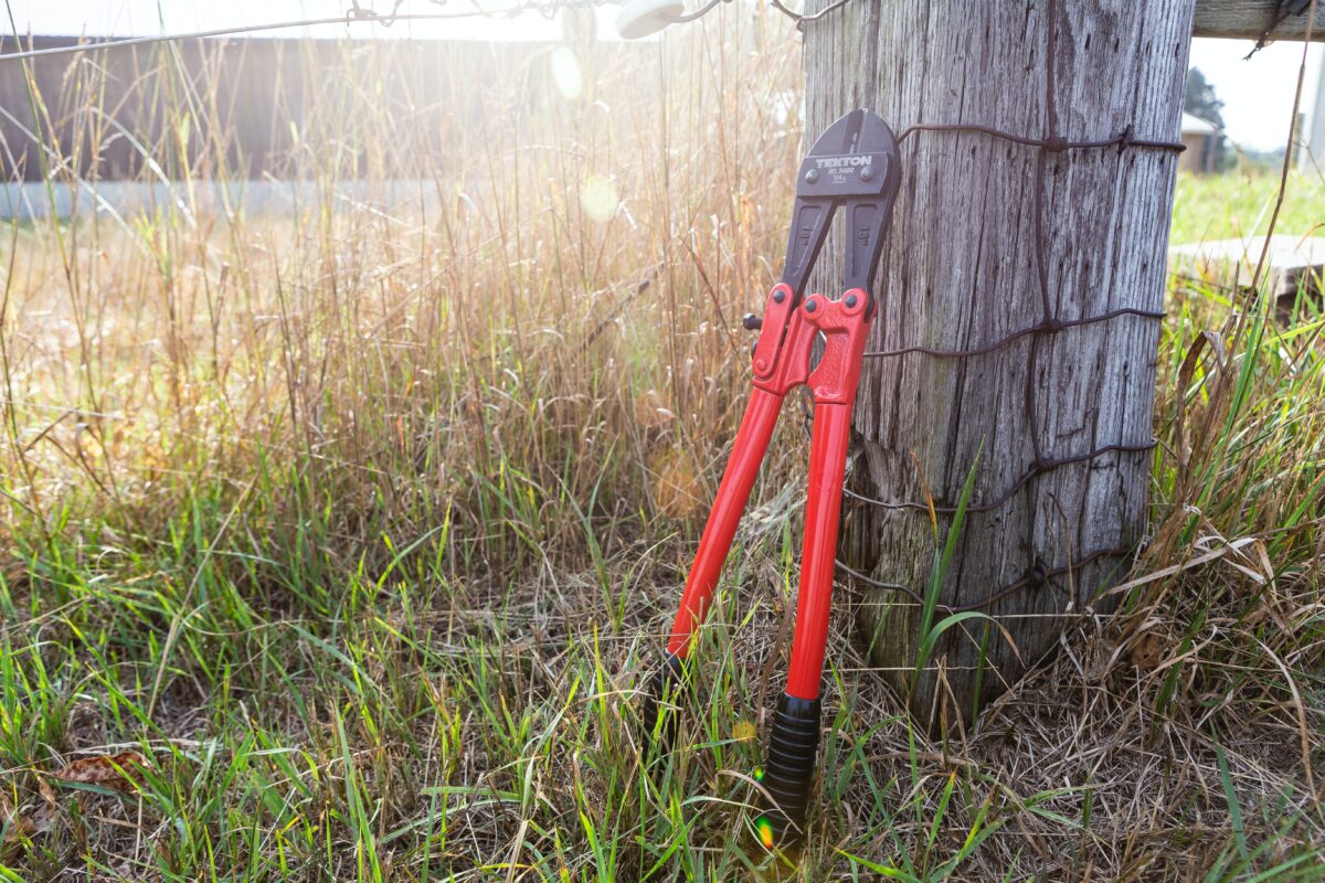 A bolt cutter leaning on a post made of wood