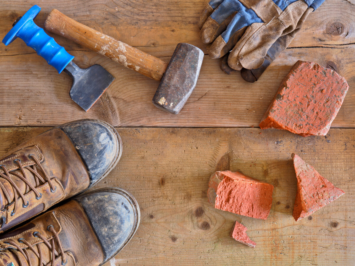 A blue handled mason chipper and stones lying in the floor