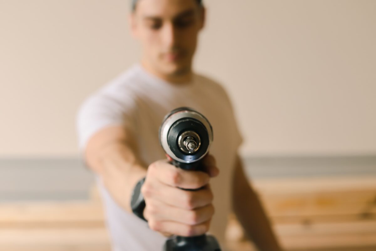 A man in white holding a drill bit faced in front