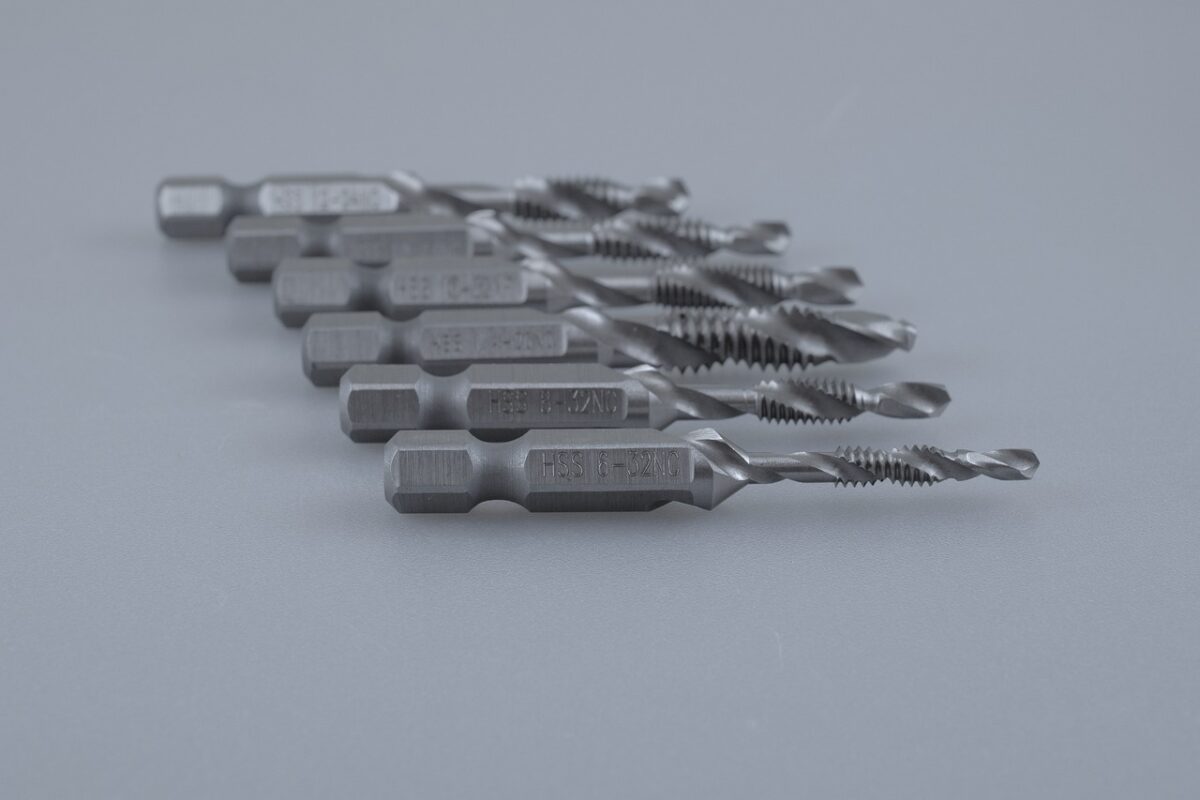 Different sizes of drill bits lined up on a white board