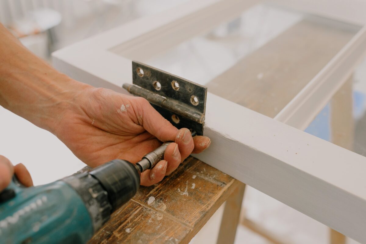 A man drilling a hinge on a door