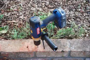 A cordless drill drilling a brick