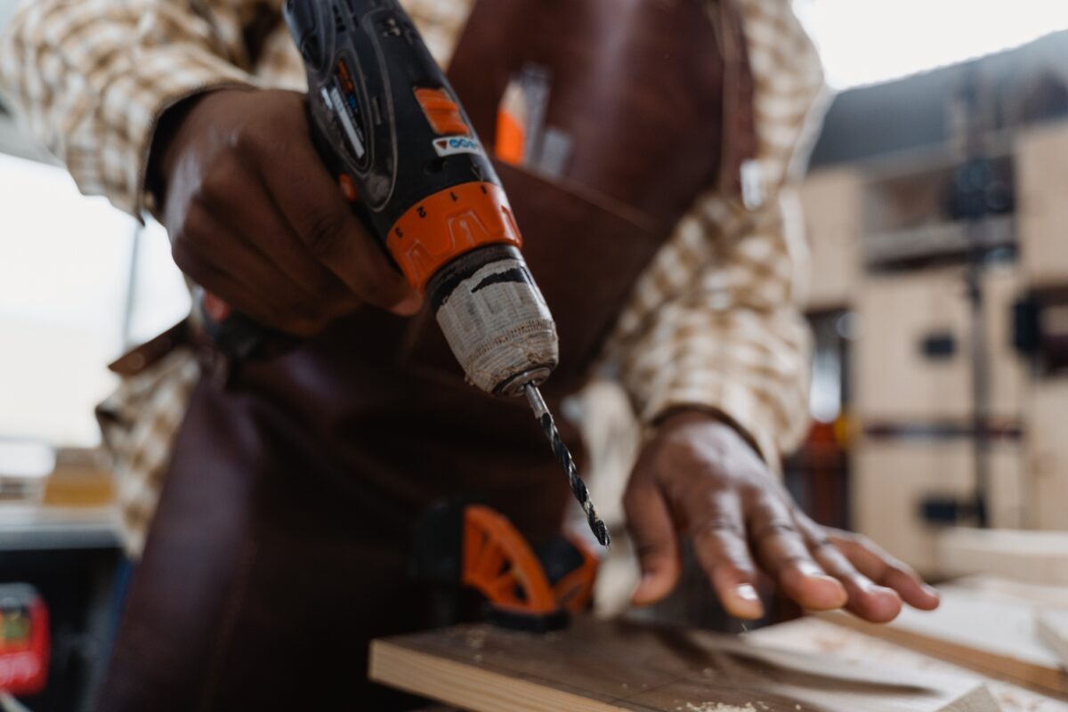 A man holding a drill about to create a hole on the wood